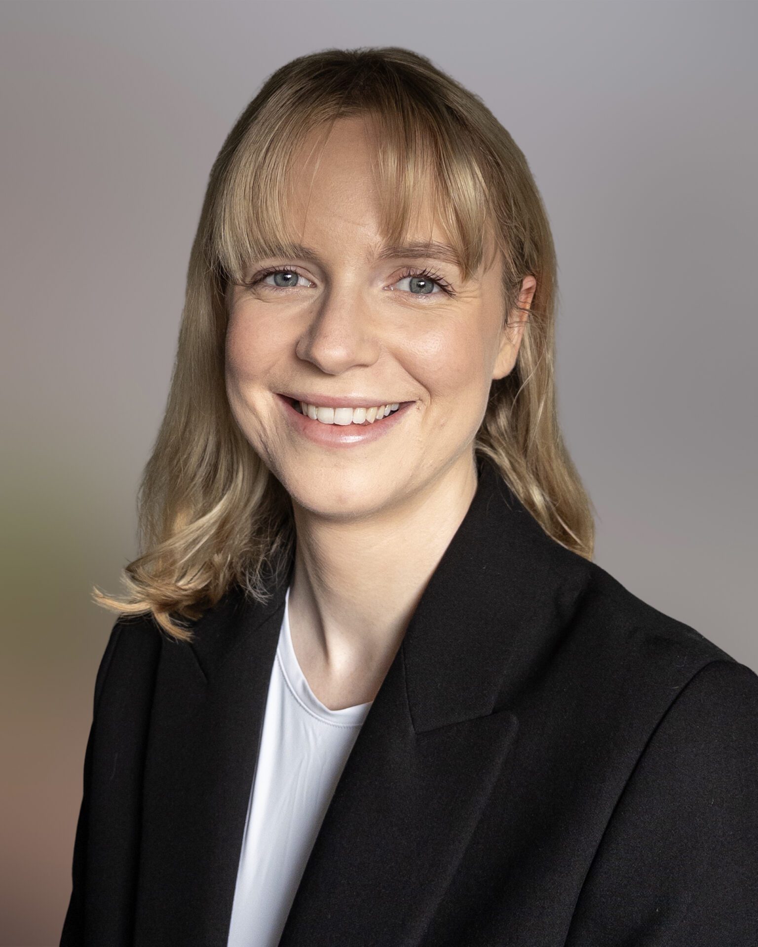 Headshot of Judith Brock, wearing her blonde hair down with a white shirt and black blazer