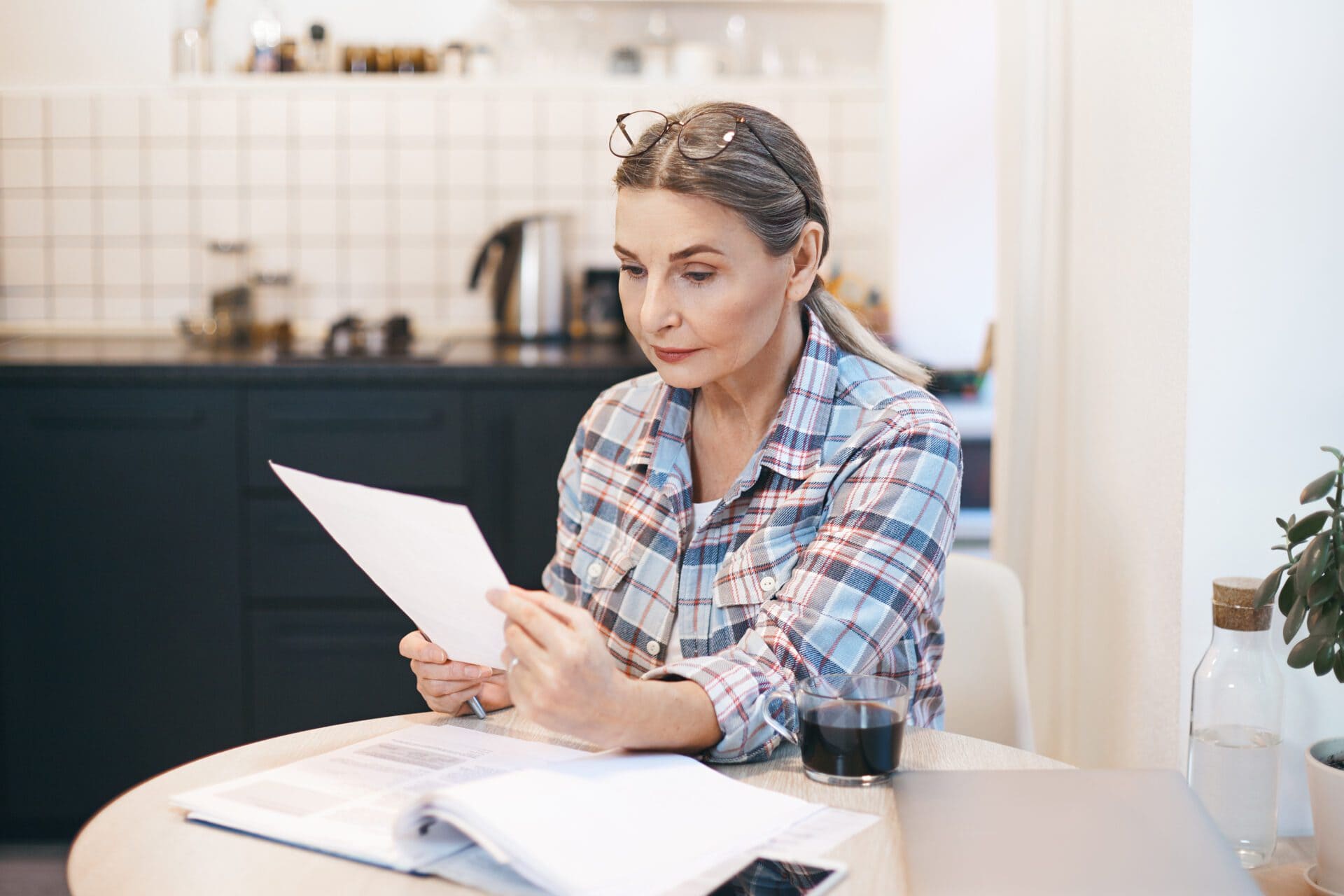 Woman sitting at a desk with papers around her, reading a document