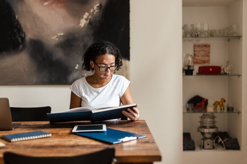Woman with curly black hair and vitiligo sat looking over her financial settlement