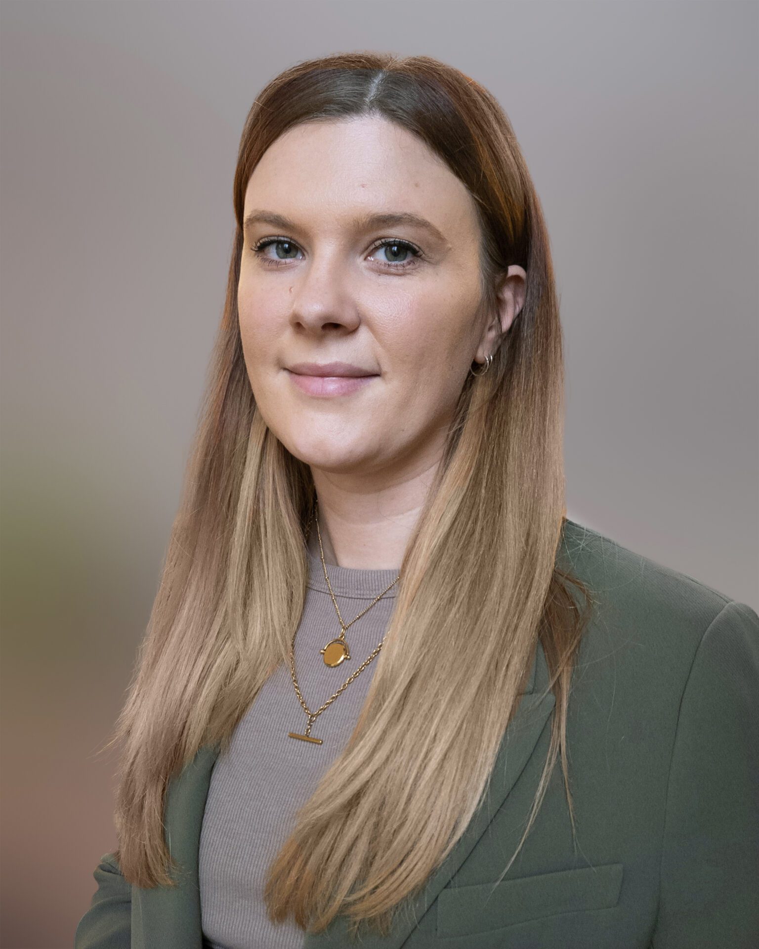 Headshot of Anna Stinton, wearing a green blazer and grey top with her blonde hair down