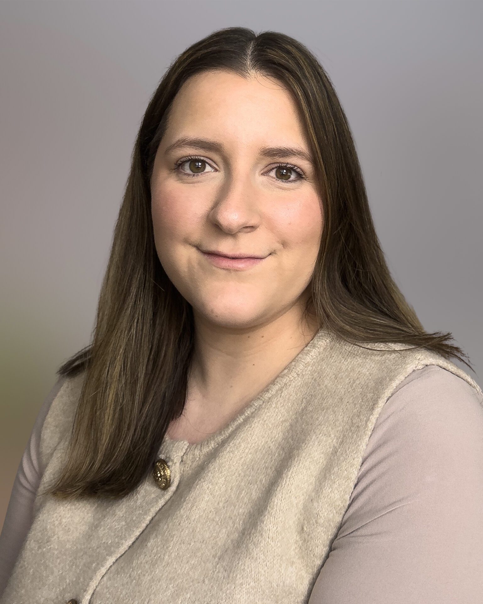 Headshot of Alexia Papachrisostomou wearing her brown hair down with a beige top